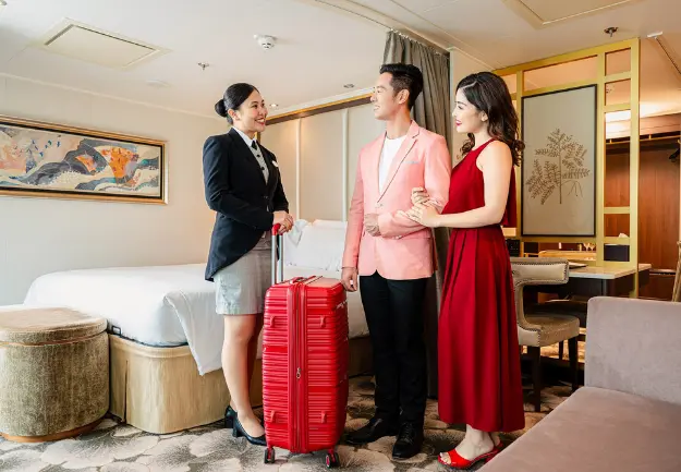 Couple being welcomed into their luxury Palace Suite by cruise staff on Genting Dream Cruise