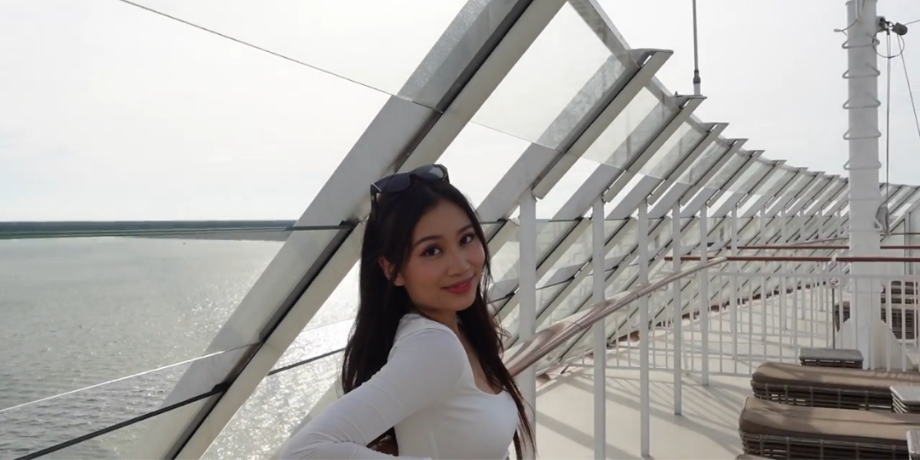 Guest posing at sunset on the upper sun deck of Genting Dream