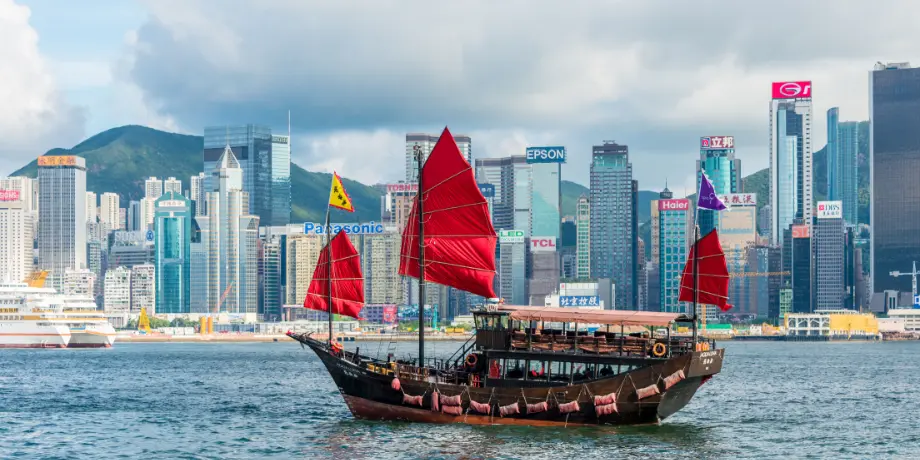 Hong Kong skyline with red-sailed junk boat – Star Voyager Cruise departure port