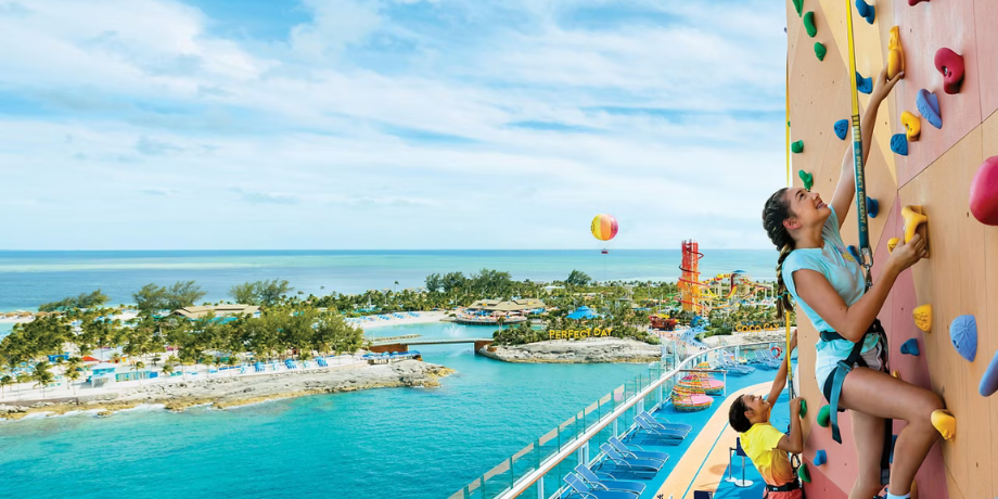 Woman and child climbing the rock wall aboard Ovation of the Seas with tropical island views Woman and child climbing the rock wall aboard Ovation of the Seas with tropical island views